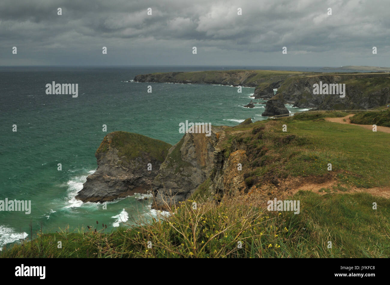 the rocks and sea at bedruthan steps national trust land or site in north cornwall showing moody slies sky and rugged coastline with surf and rocky Stock Photo