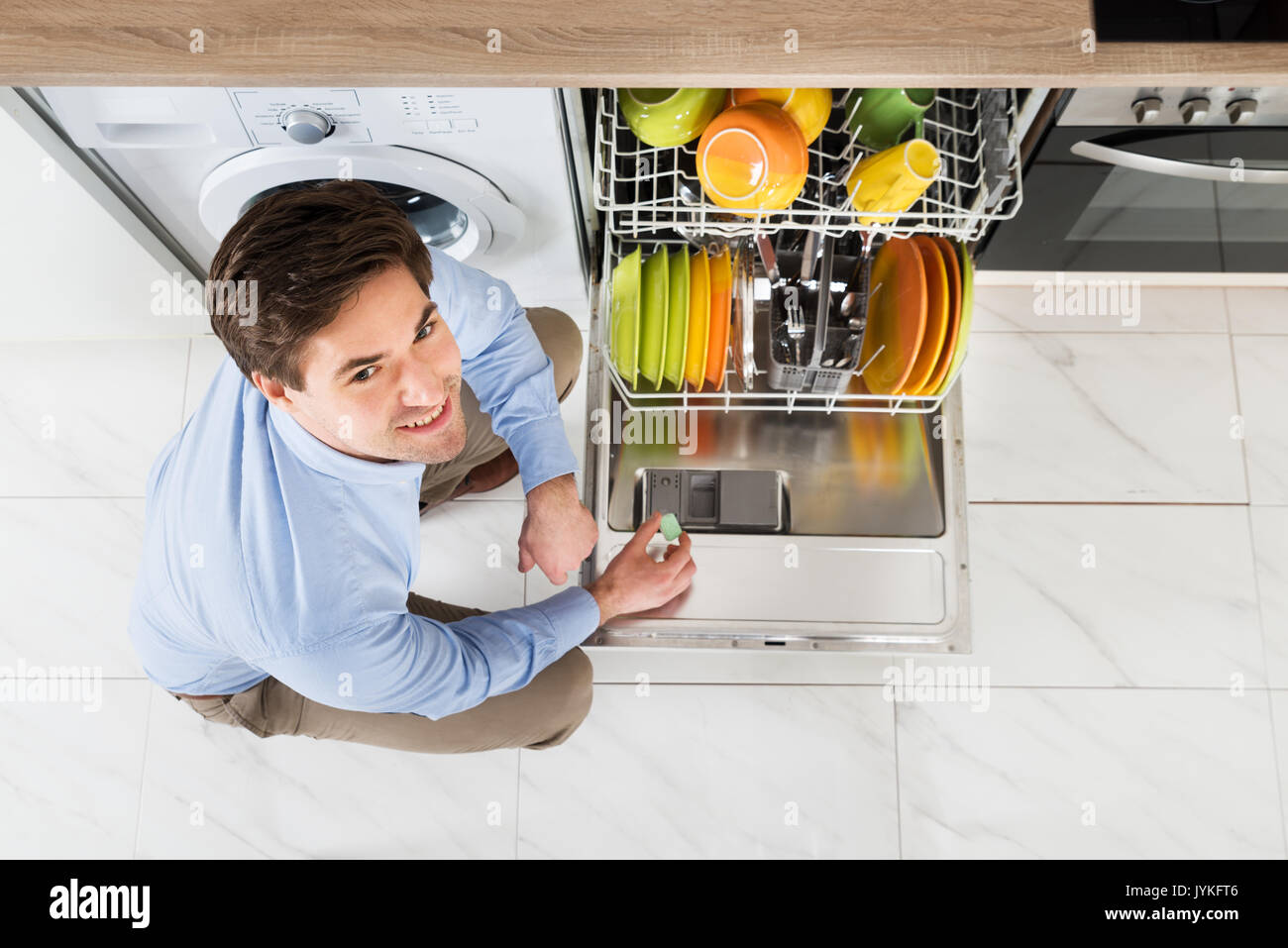 Young Man Putting Dishwasher Soap Tablet In Dishwasher Detergent Box