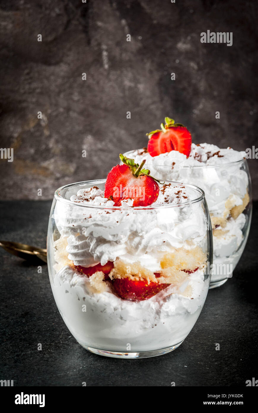 Layered dessert parfait in a glass with strawberries, sponge cake and