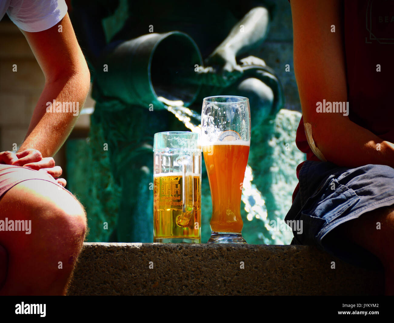 Tourists sitting at water fountain drinking beer at Marienplatz Munich Germany Europe Stock Photo