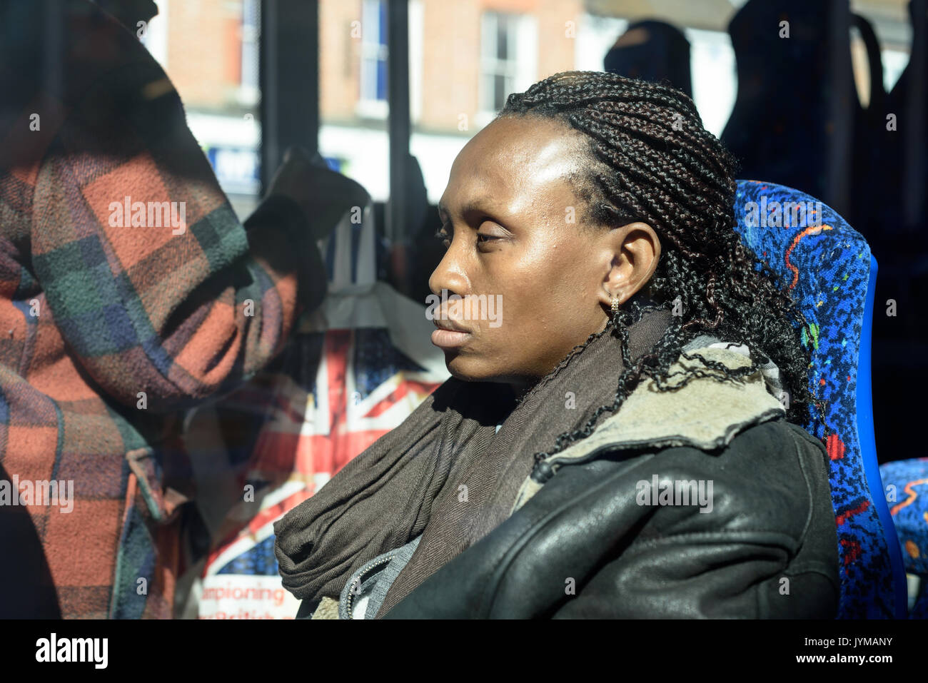 Sleepy black woman with dreadlocks hair sitting on a bus in bright sunshine Stock Photo