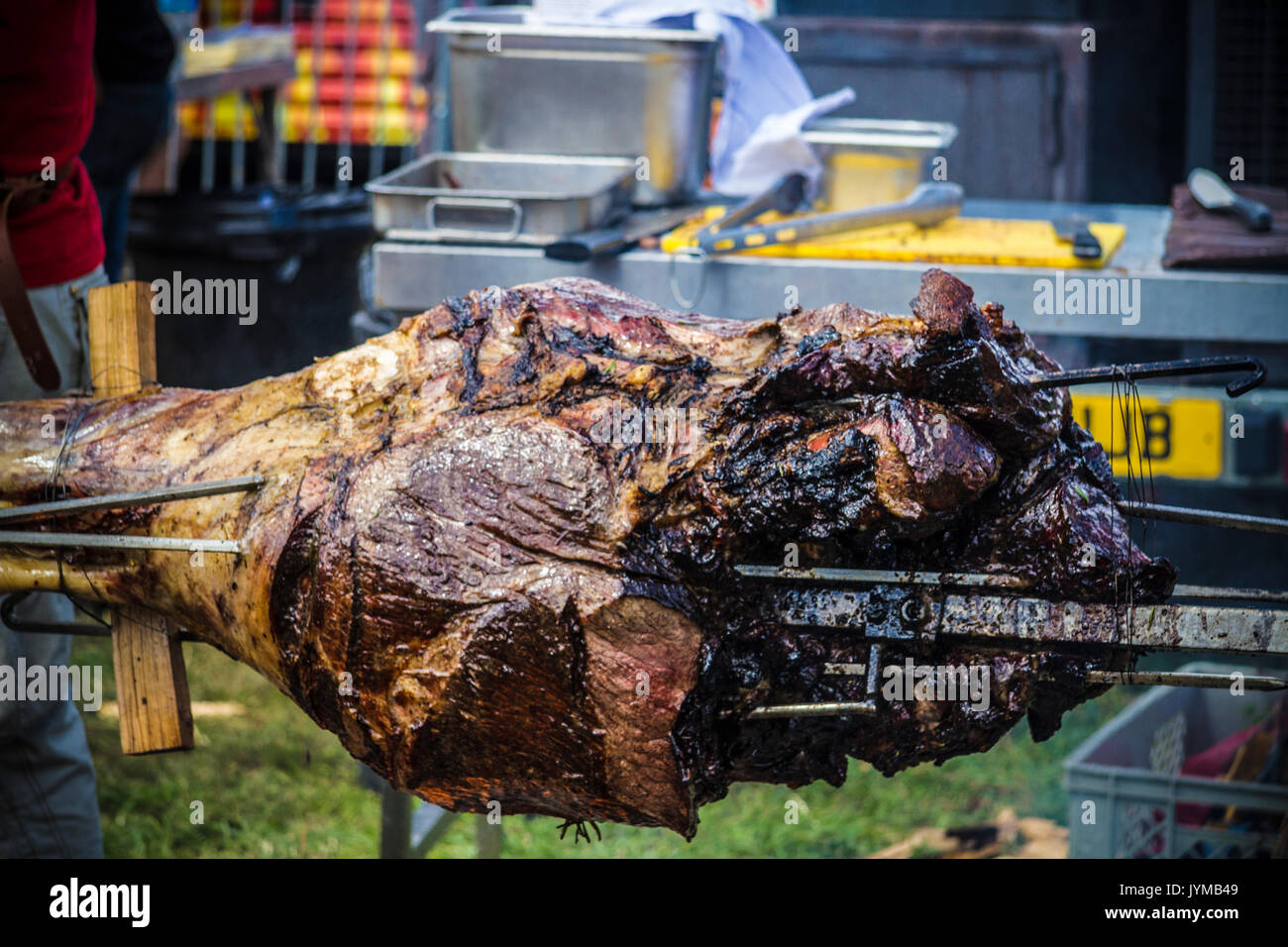 Joint of meat being spit roasted on a charcoal fire Stock Photo