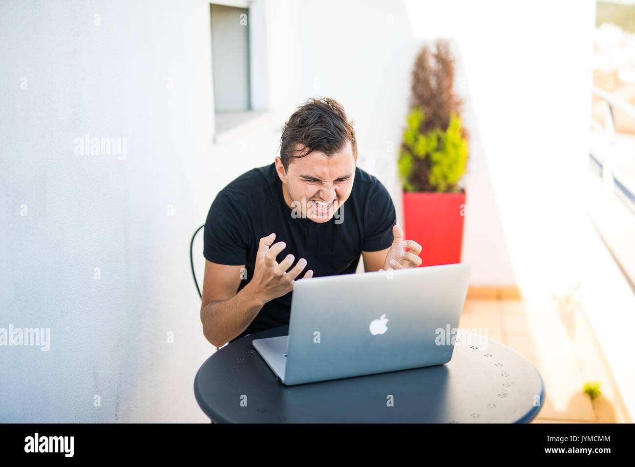 Young man working on laptop with outdoors view. Stock Photo