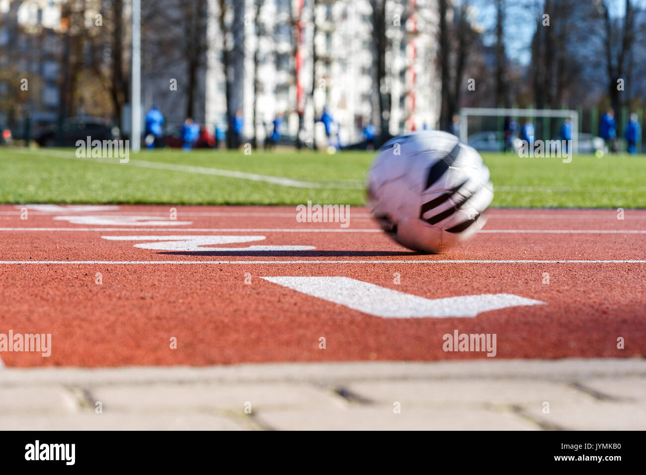 Red running track, soccer ball in motion, Blurred soccer players Stock