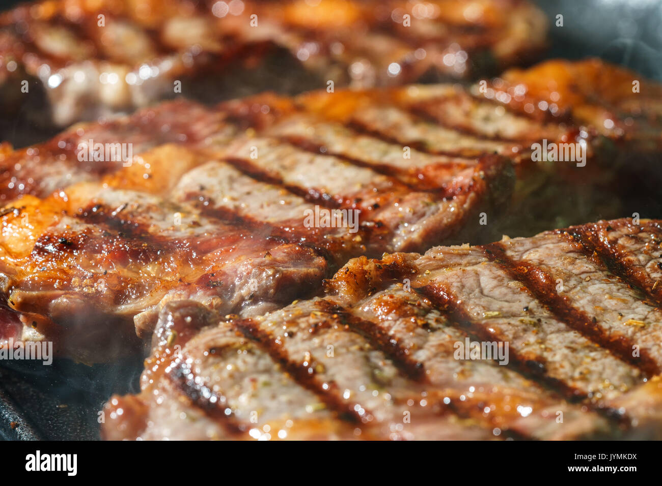 Raw Ribeye Steak with Herbs and Spices, frying on grill pan Stock Photo