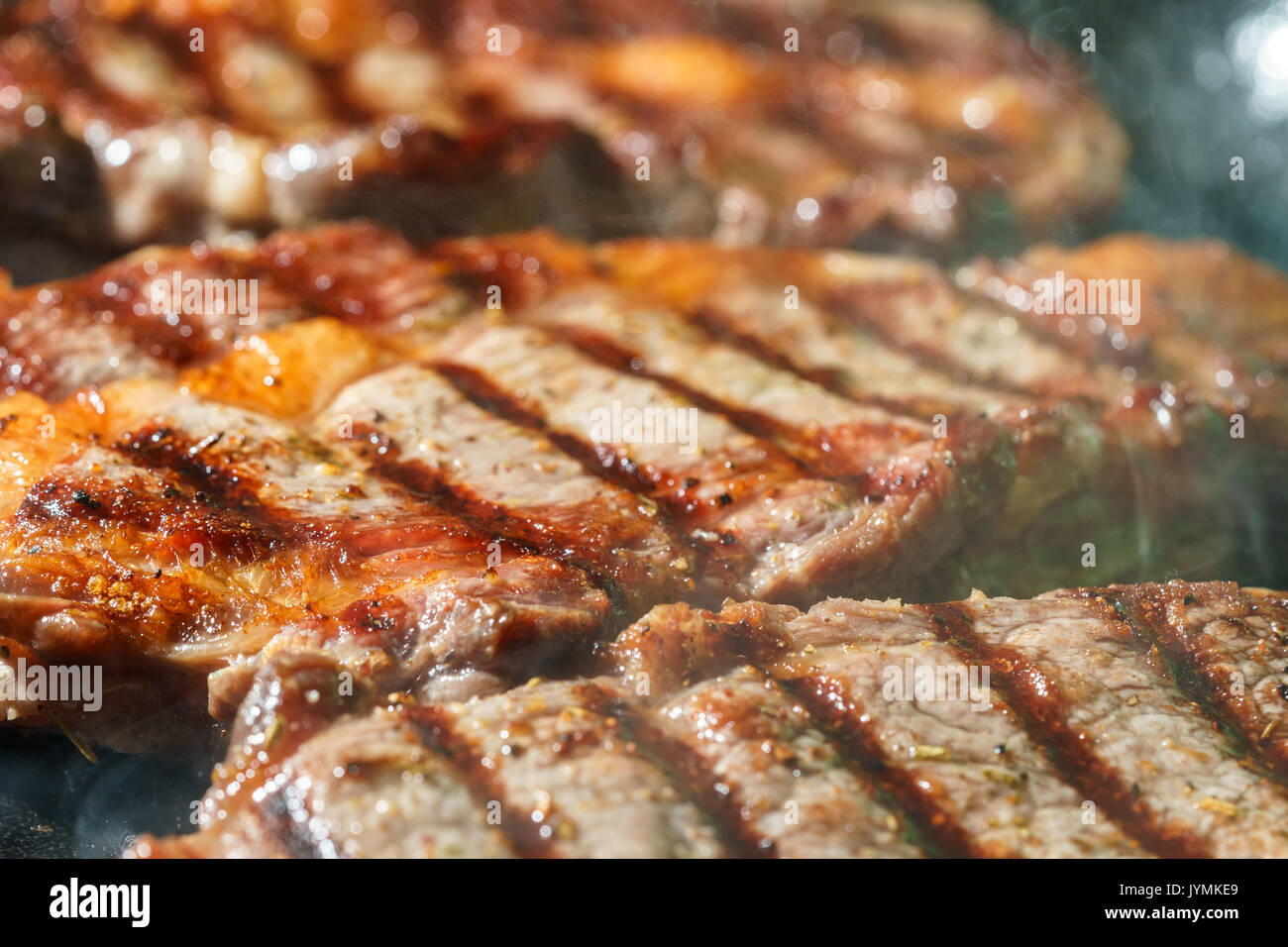 Raw Ribeye Steak with Herbs and Spices, frying on grill pan Stock Photo