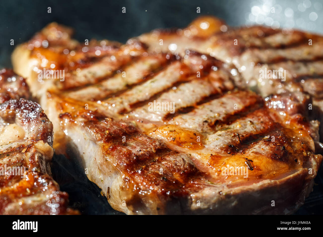 Raw Ribeye Steak with Herbs and Spices, frying on grill pan. Stock Photo