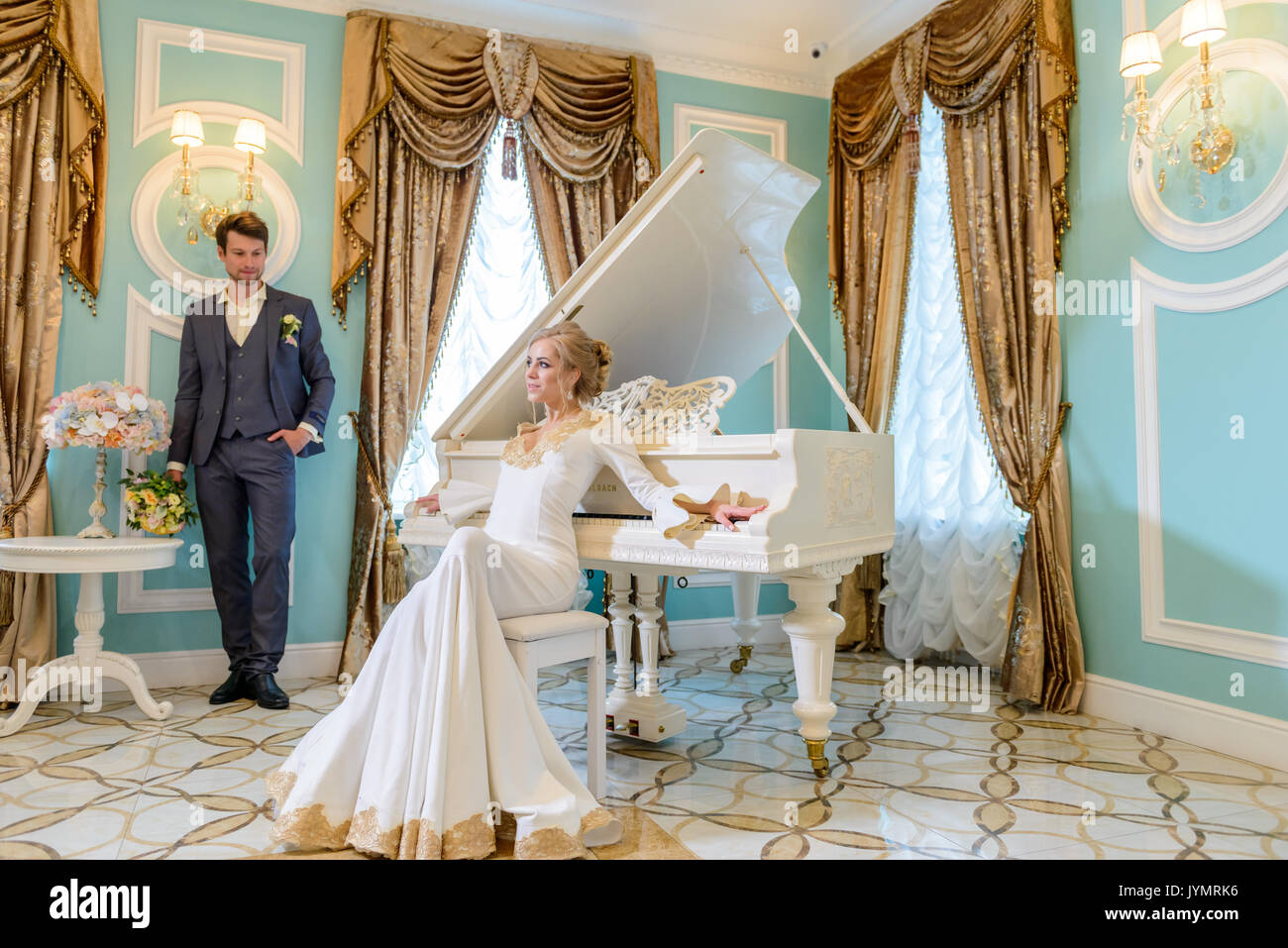 bride and groom near the white piano Stock Photo