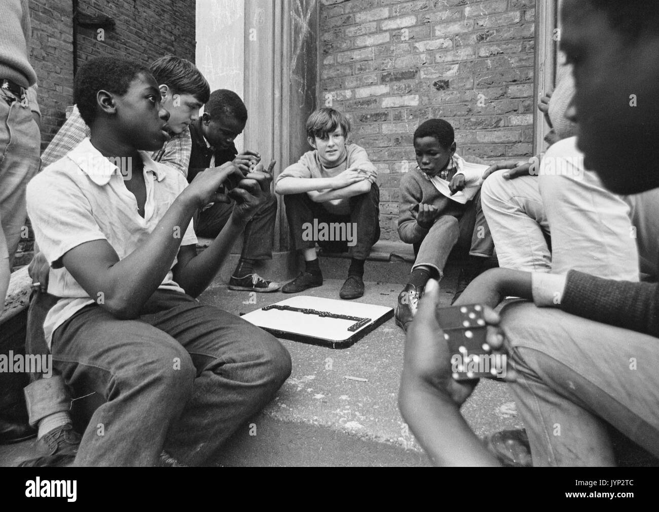 Children playing dominoes in an interracial group in Brixton, England, 1966 Stock Photo