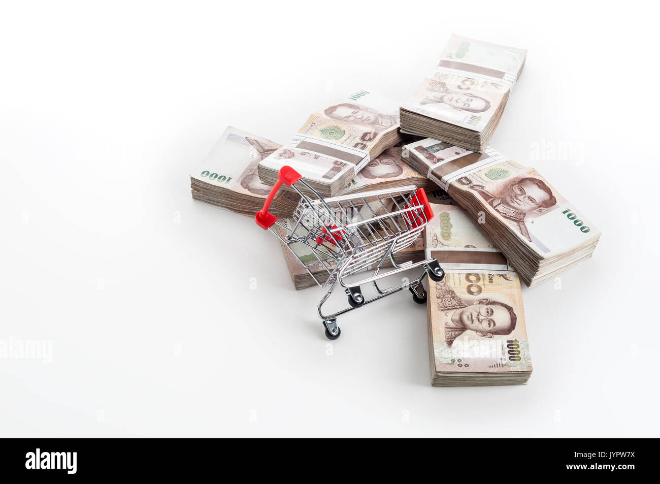 Empty shopping cart in front of heap of Thai baht (THB) banknotes. Thailand currency. Stock Photo