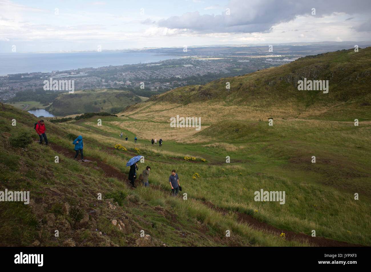 Walkers descending the peak. The peak of King Arthur's Seat is a popular destination for both locals and tourists. The peak and souronding rocky hills Stock Photo