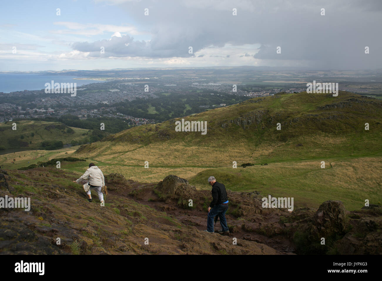 Walkers descending the peak. The peak of King Arthur's Seat is a popular destination for both locals and tourists. The peak and souronding rocky hills Stock Photo