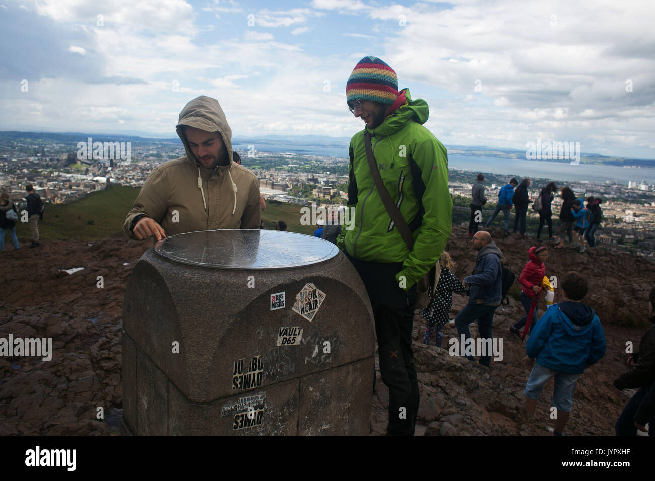Tourists look at the map of the surrounding landscape on top of the peak. The peak of King Arthur's Seat is a popular destination for both locals and  Stock Photo