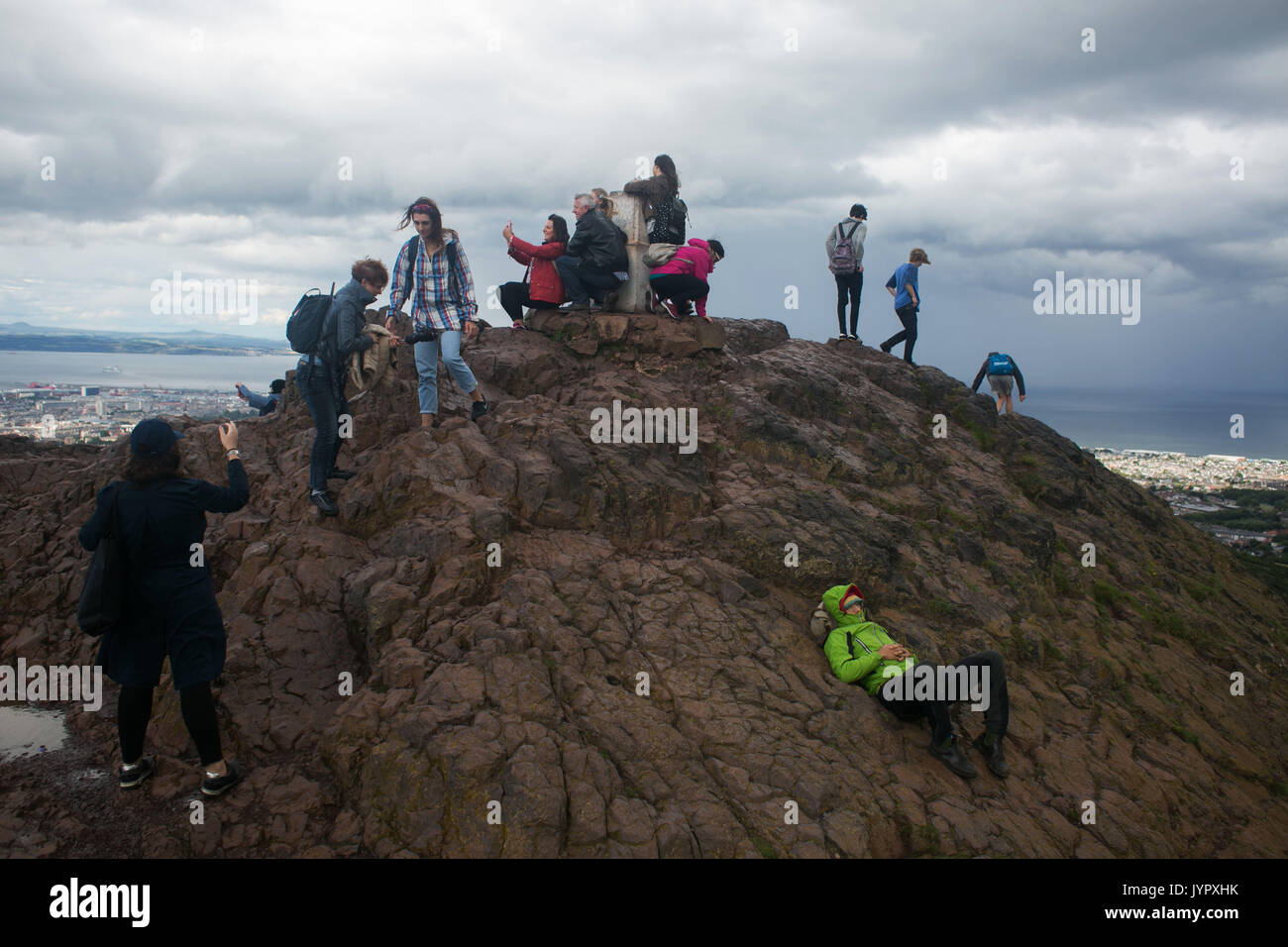 Visitors crowd together on the top of the peak. The peak of King Arthur's Seat is a popular destination for both locals and tourists. The peak and sur Stock Photo