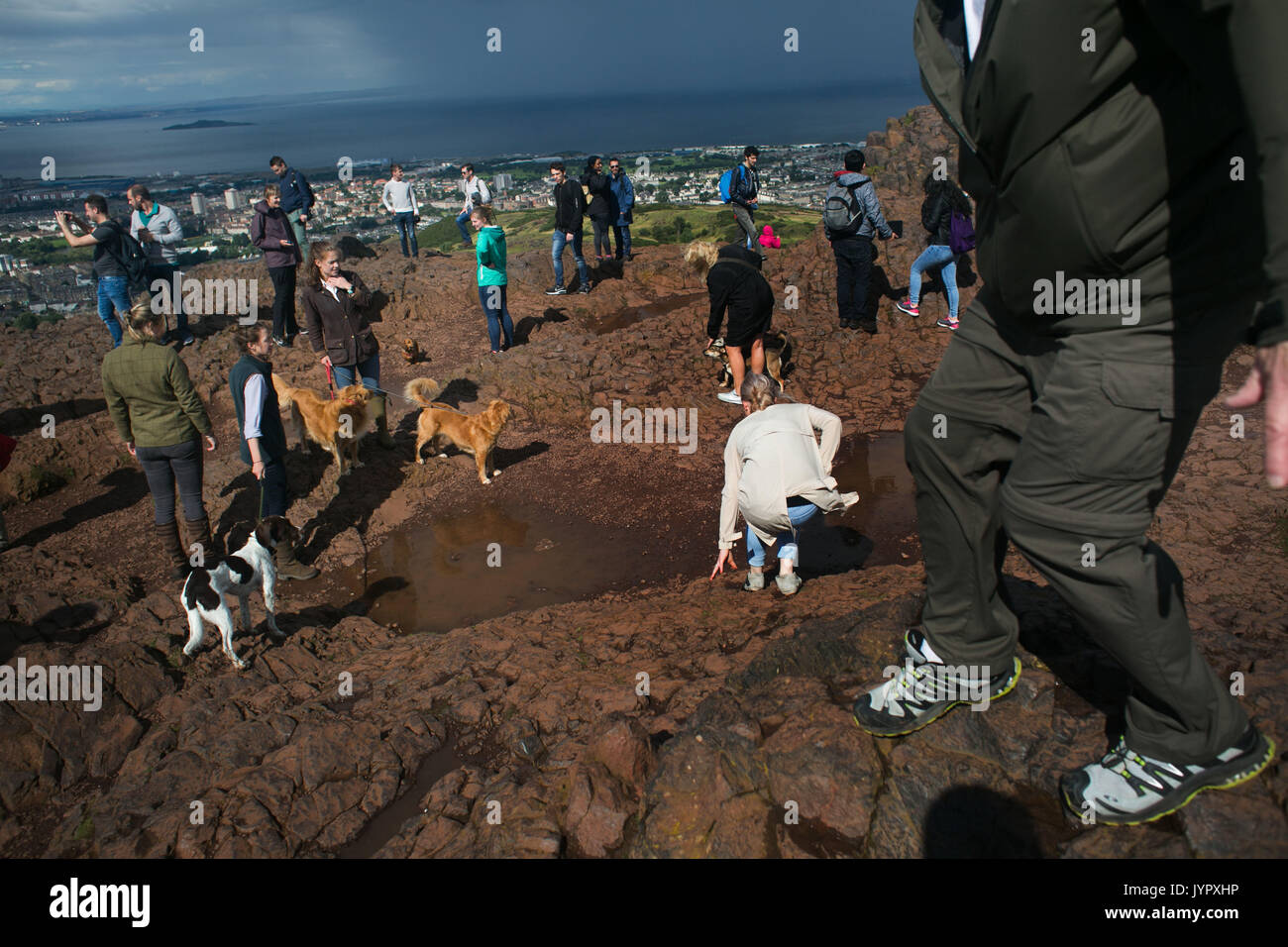 Visitors crowd together on the top of the peak. The peak of King Arthur's Seat is a popular destination for both locals and tourists. The peak and sou Stock Photo