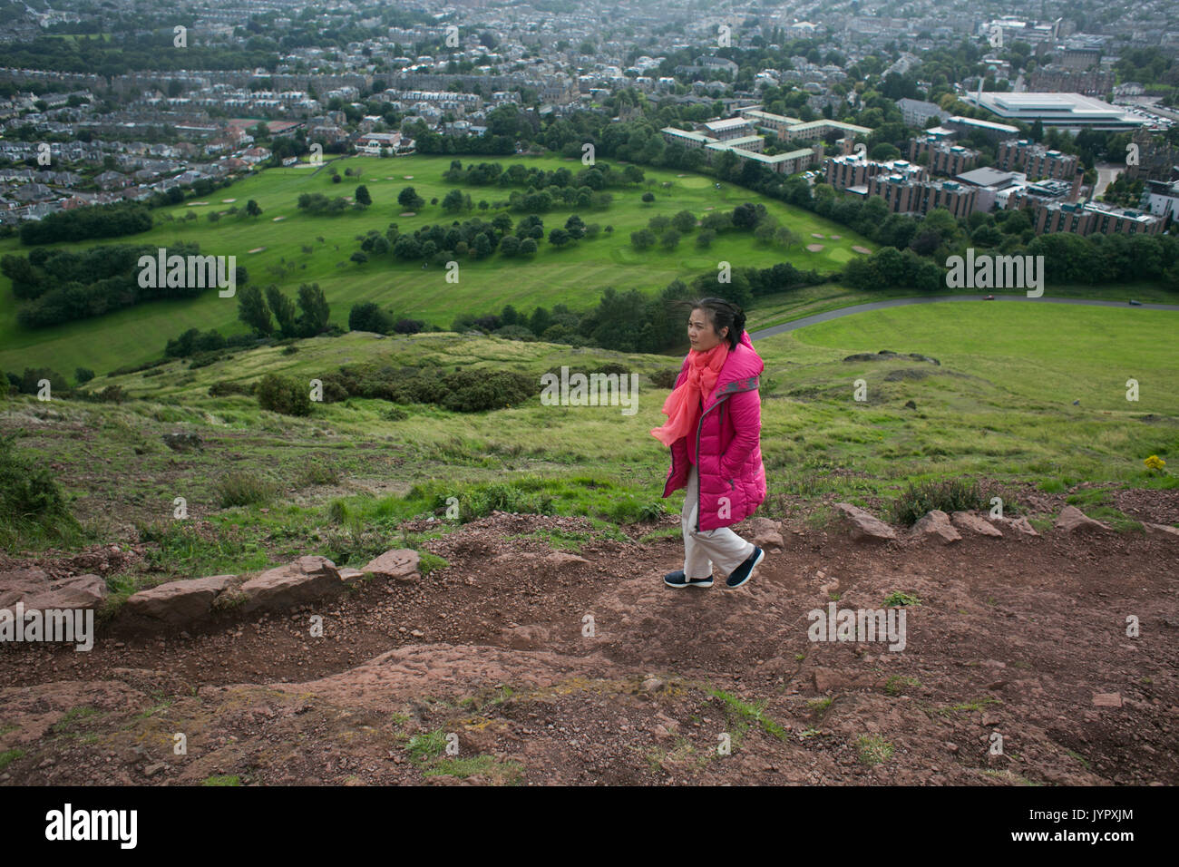 An Asian tourist makes her way up to the top of the peak. Rain is coming. The peak of King Arthur's Seat is a popular destination for both locals and  Stock Photo