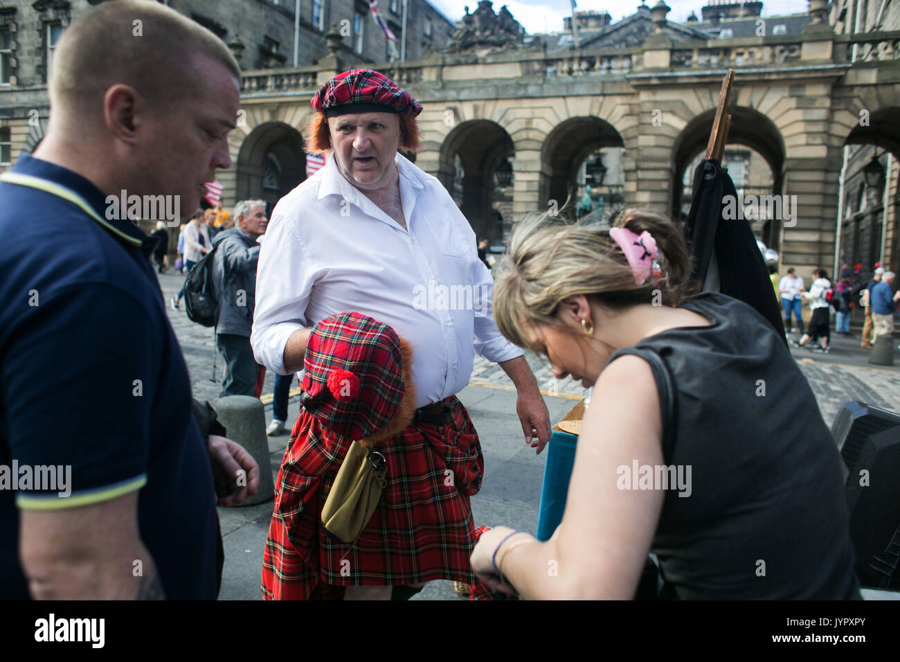 A busker sells the Scottish look, kilt and a Jimmy Wig to tourists in the Royal Mile. Edinburgh international and fringe festival in full swing. Stock Photo