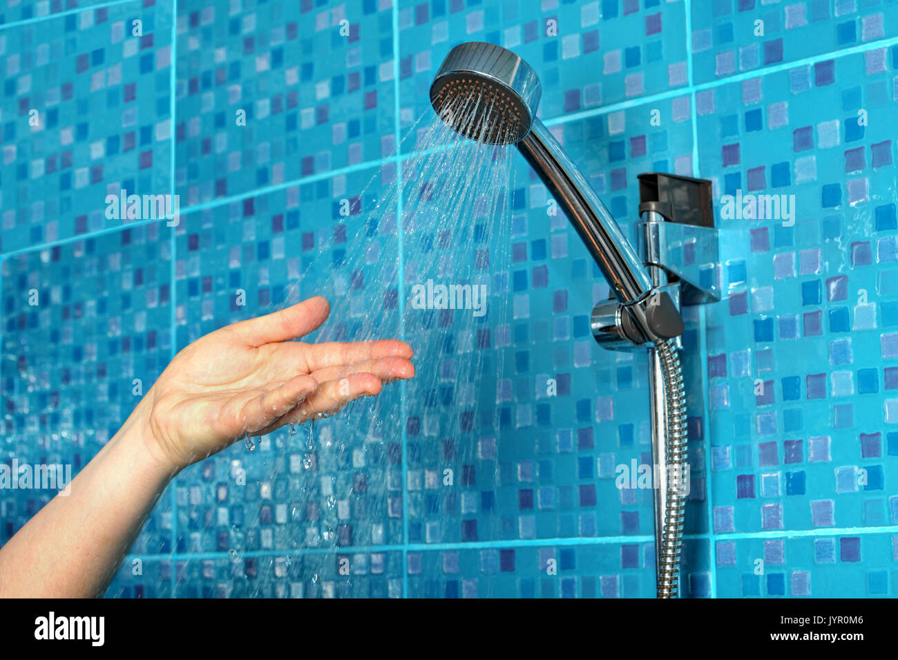Closeup of a woman's hand check water temperature in the shower with