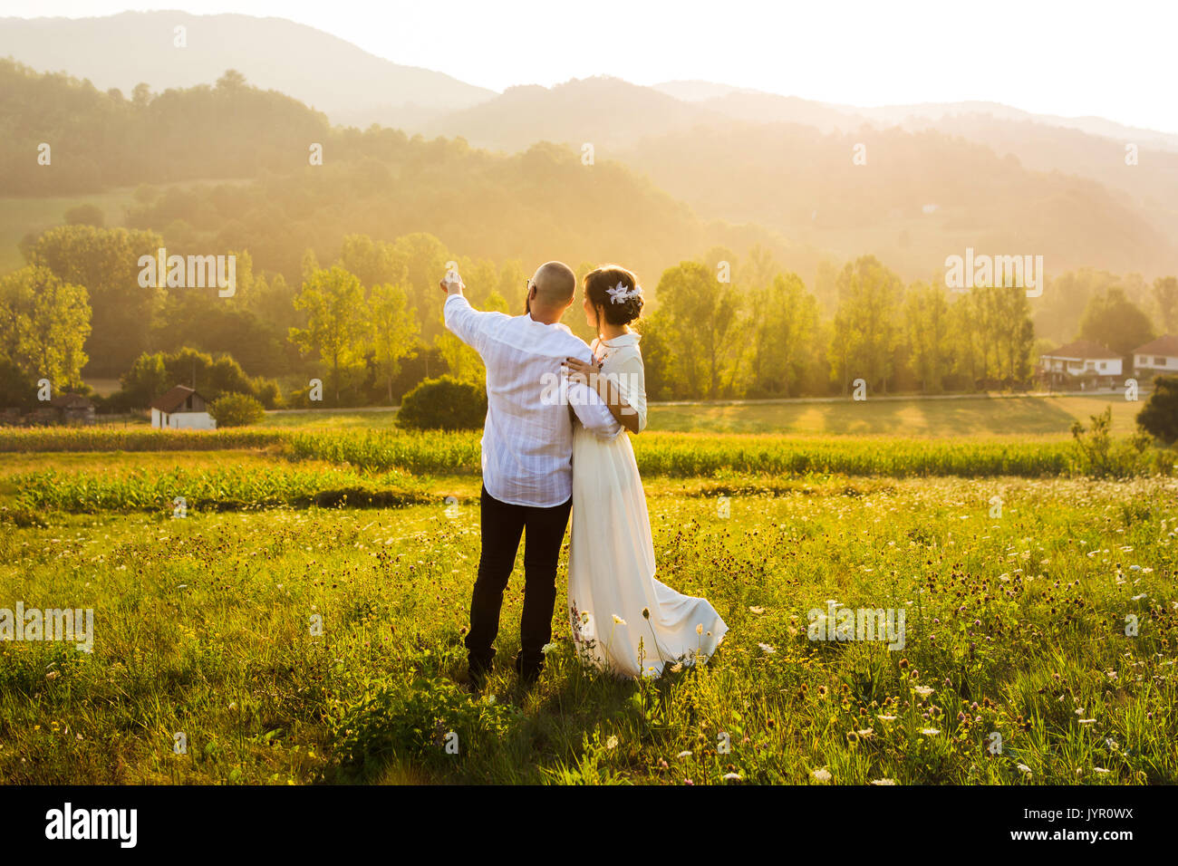 Couple enjoying romantic sunset view in the field Stock Photo