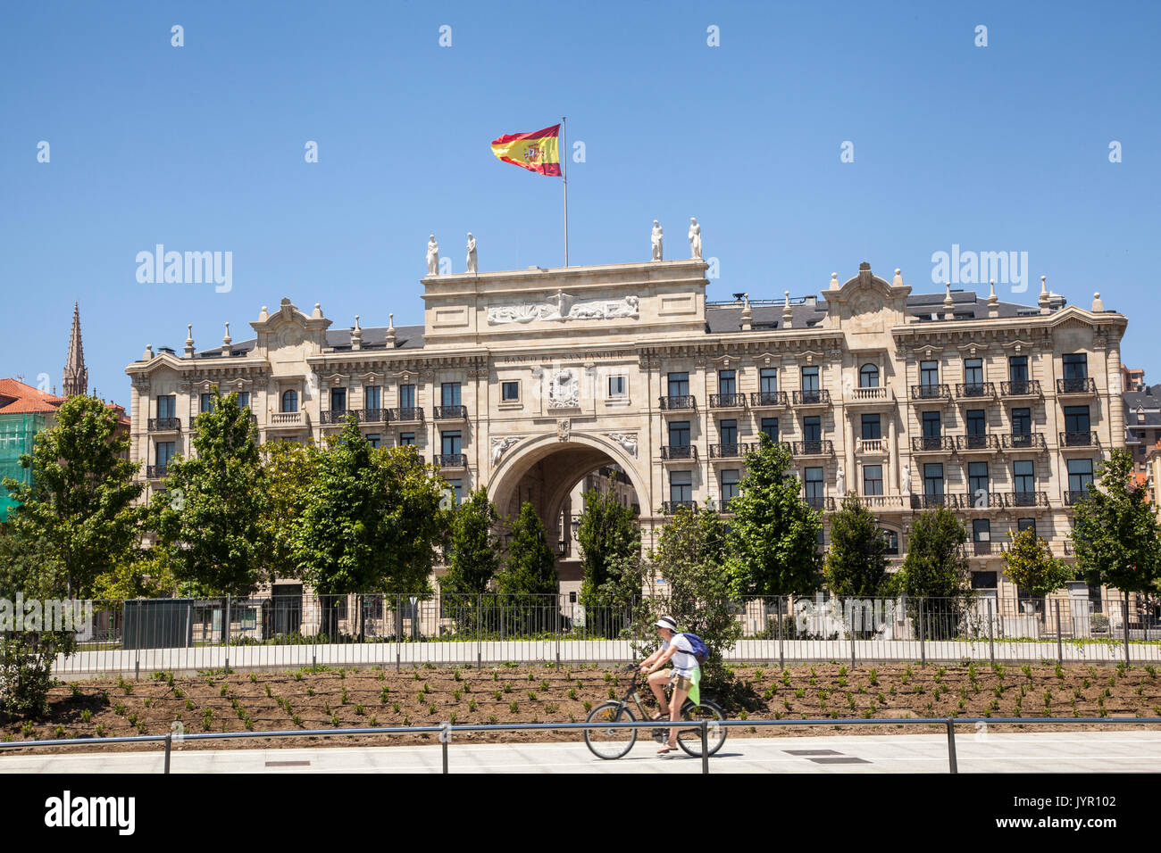 Cyclist  riding past the headquarters of the Santander bank/ Banco Santander in Santander Spain Stock Photo