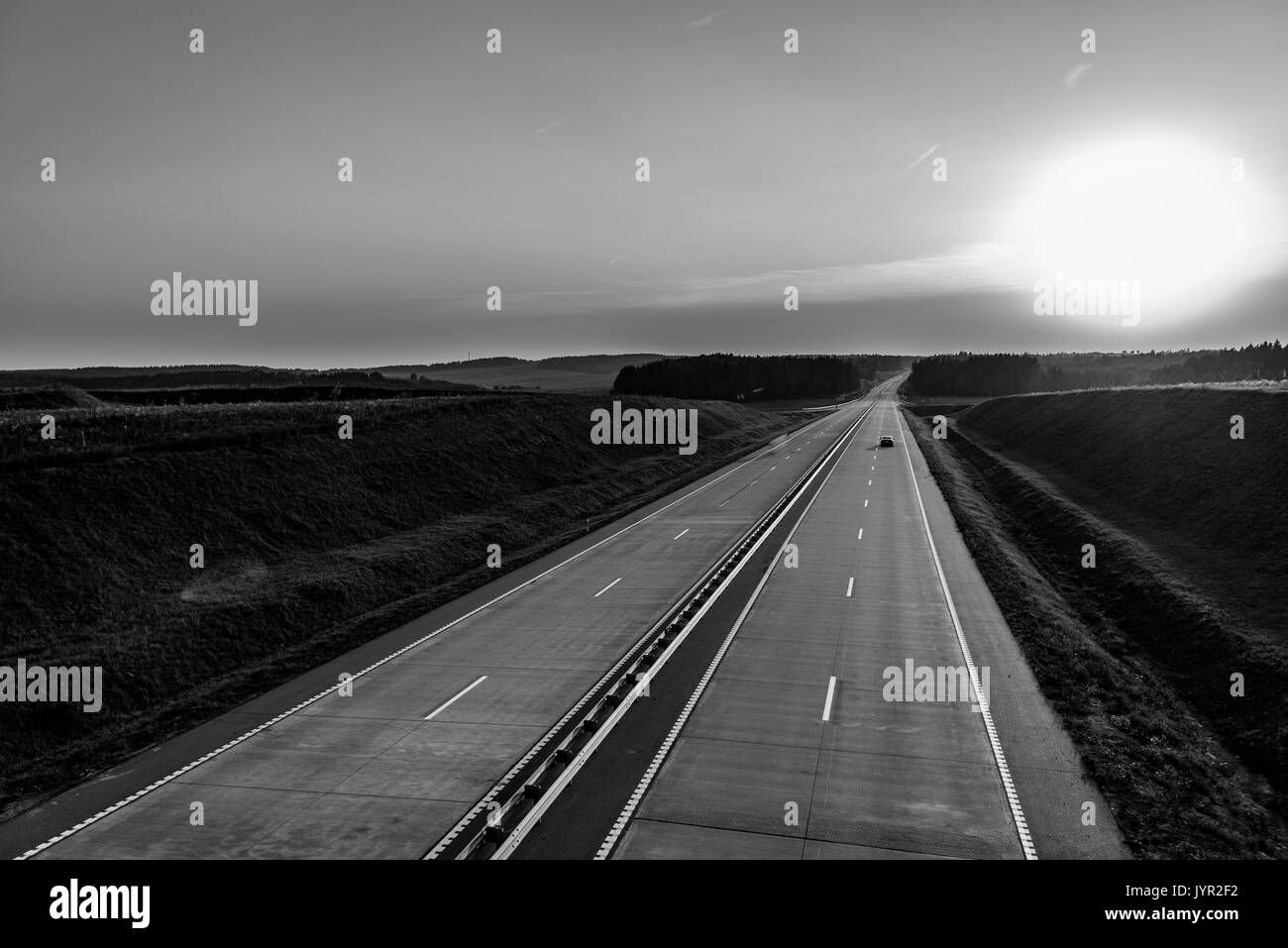 Country highway and sunset. Clear road great nuture around. Horizontal black and white view Stock Photo