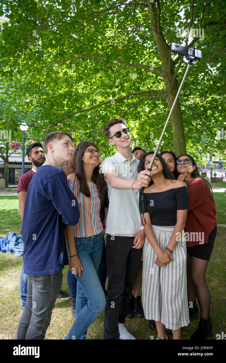 Group of young British people youths posing for a selfie using a selfie stick in a park Stock Photo
