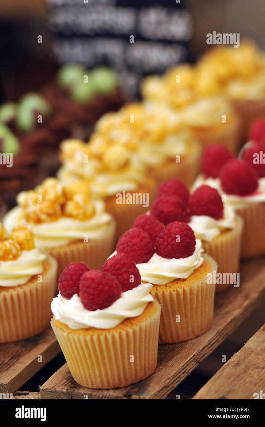 Some gluten free sticky cream and iced icing cakes on display on a cake stand sweet sugary produce for sale very tempting deserts and confections Stock Photo