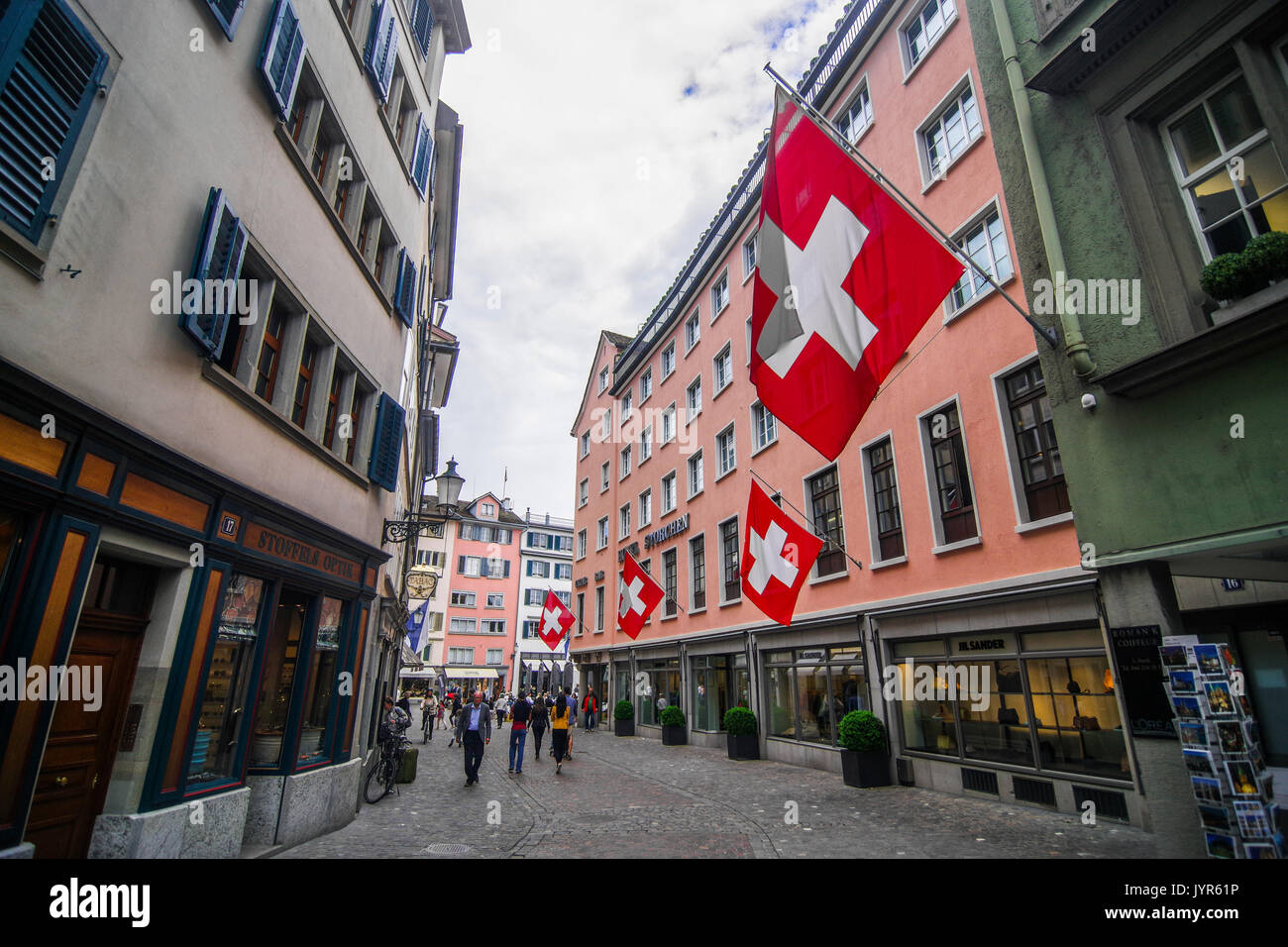 Downtown City scene of narrow shopping street with many Swiss flags