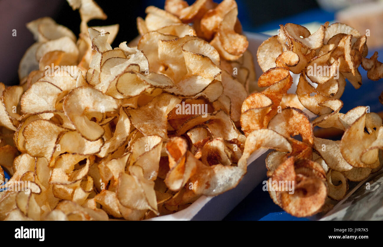 Hot deepfried potato chips from the midway overflow from a basket onto