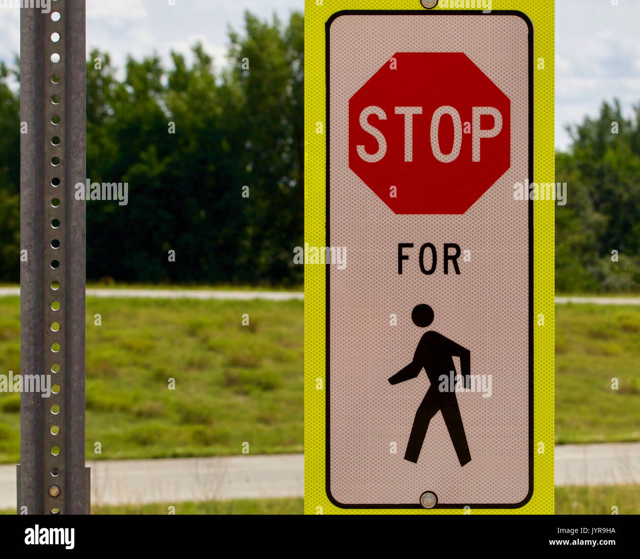 Stop for pedestrian sign against a green background Stock Photo