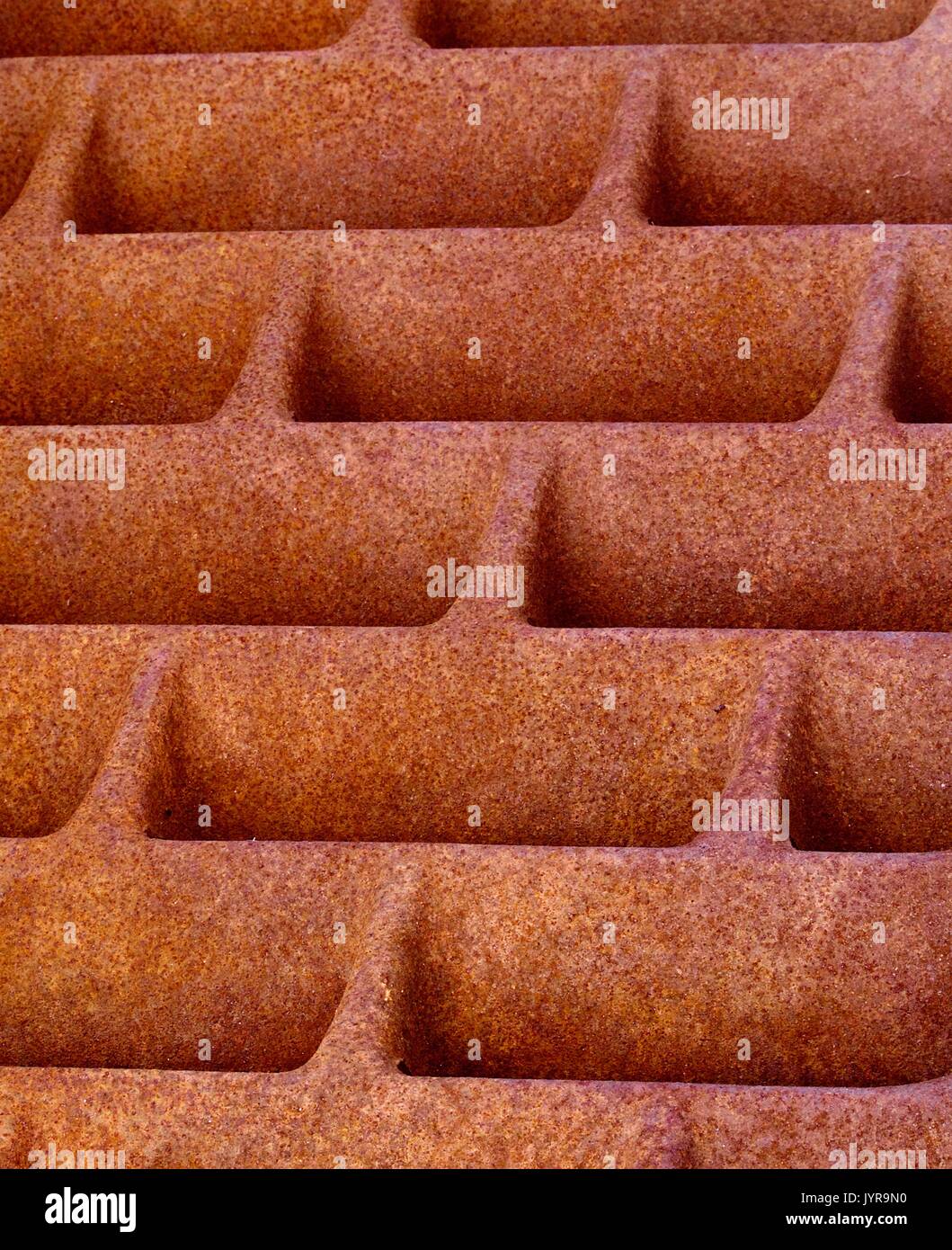 Heavy iron sewer grid cover with orange rust Stock Photo