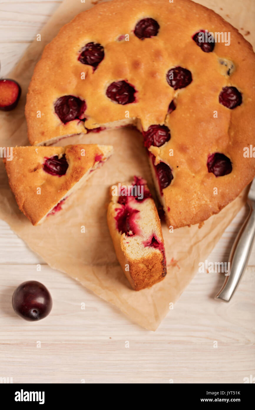 Home plum pie on baking paper. Selective focus. Stock Photo