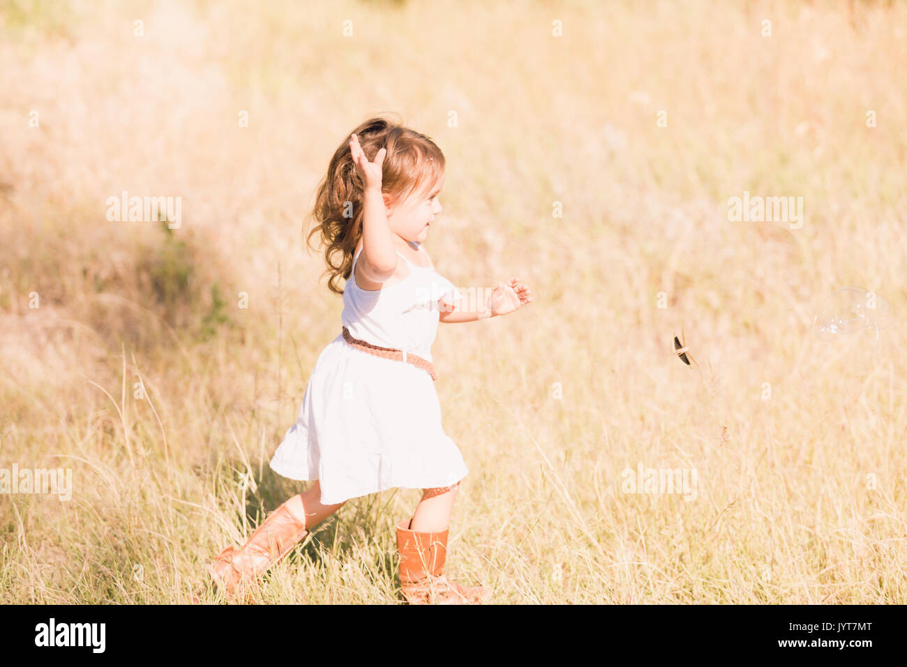 Little girl in a white sun dress playing outside Stock Photo Alamy