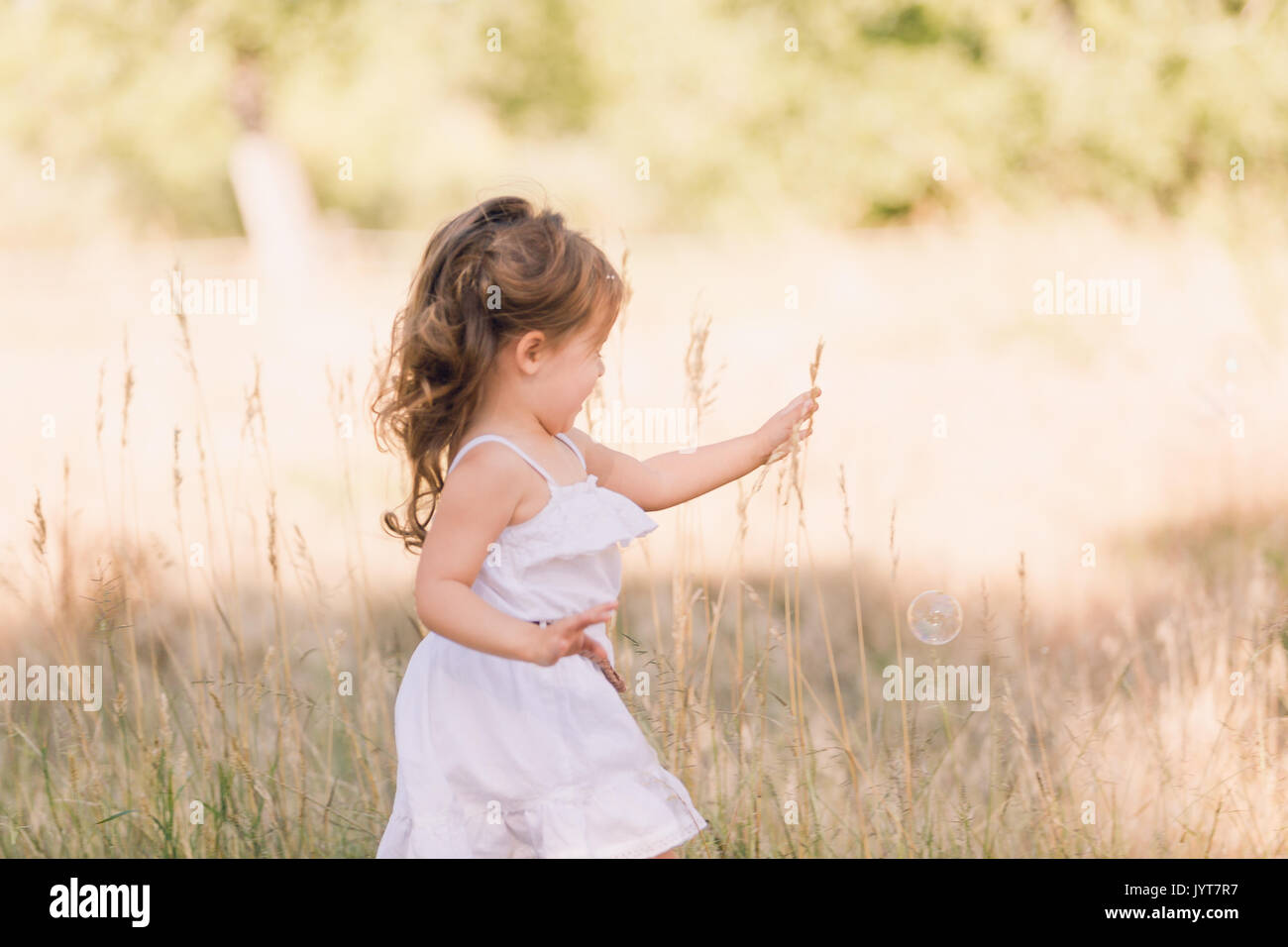 Little girl playing with soap bubbles in the park Stock Photo - Alamy