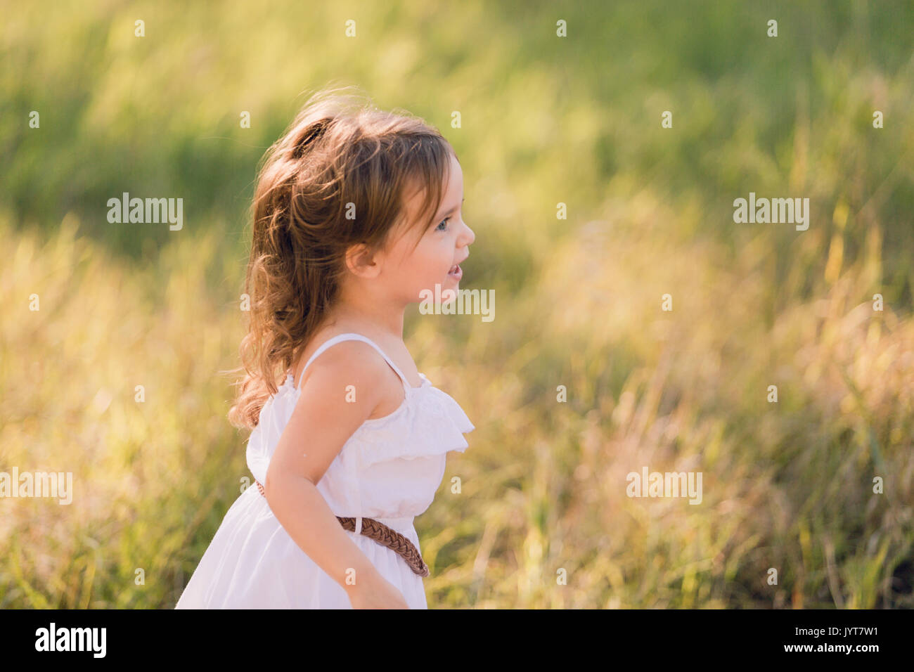 Little girl in a white sun dress playing outside Stock Photo Alamy