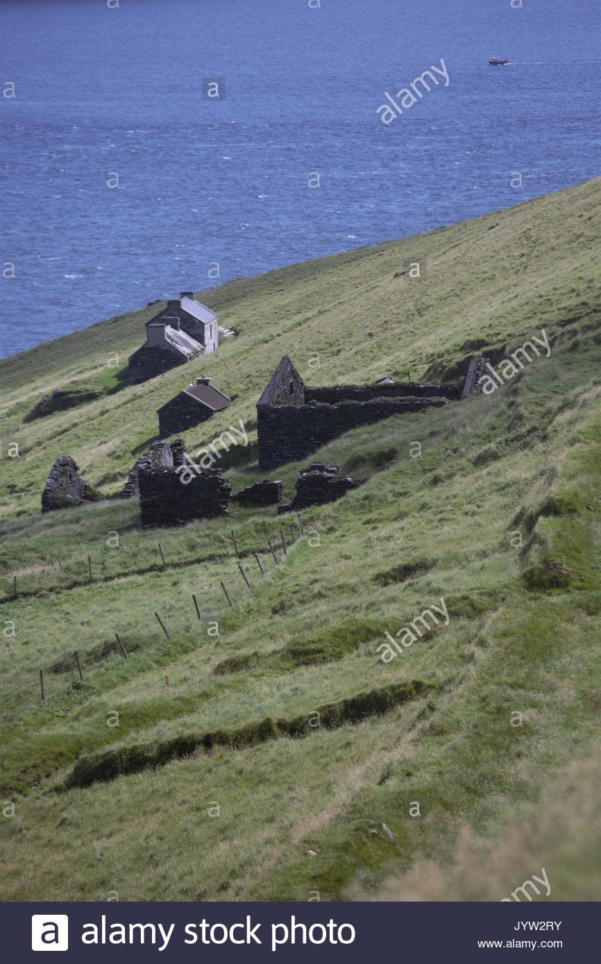 A view of the Great Blasket Island off the West Coast of ireland showing stone houses in which people lived and the Blasket Sound stretch of the ocean Stock Photo