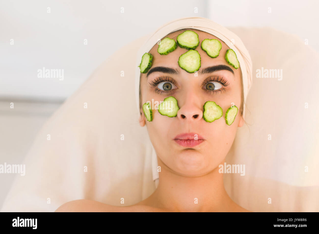 Cucumber slices on eyes. Young woman with facial mask of cucumber in