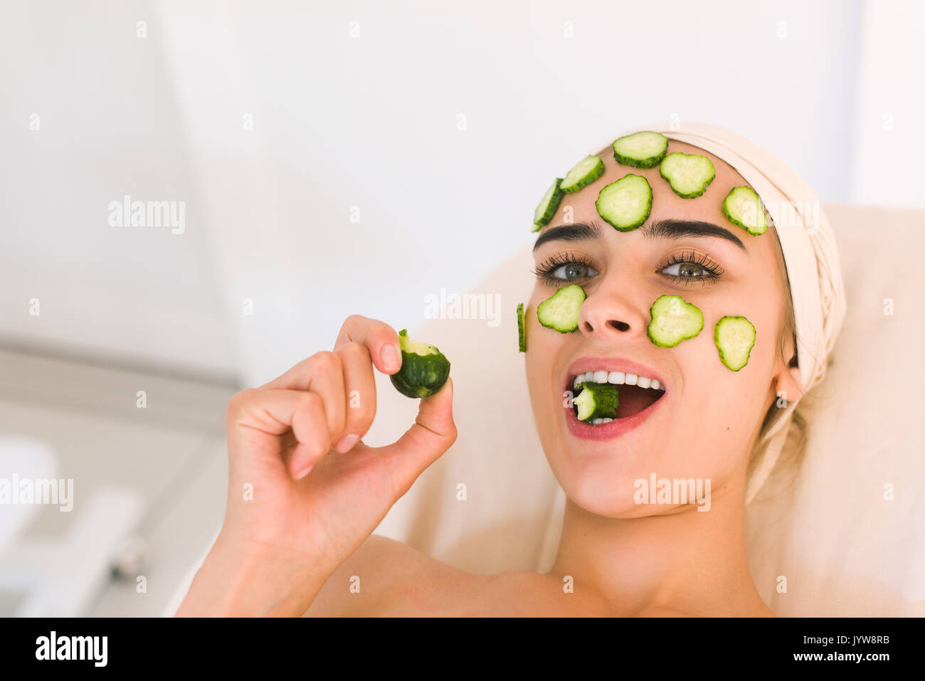 Cucumber slices on eyes. Young woman with facial mask of cucumber in