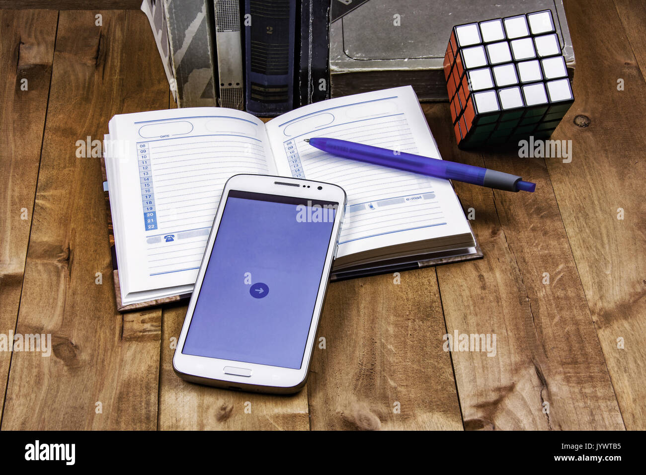 Books, diary with pen, smartphone and cube Rubik lie on a wooden surface Stock Photo