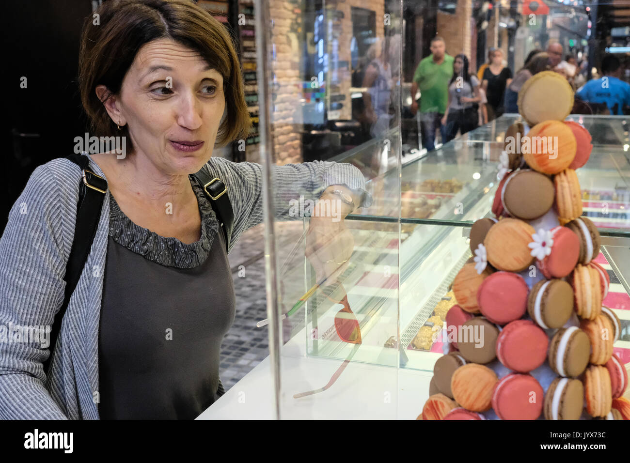 A woman admires colorful macaroons on sale at a stand in Sarona Market, Israel's largest indoor culinary market. Stock Photo