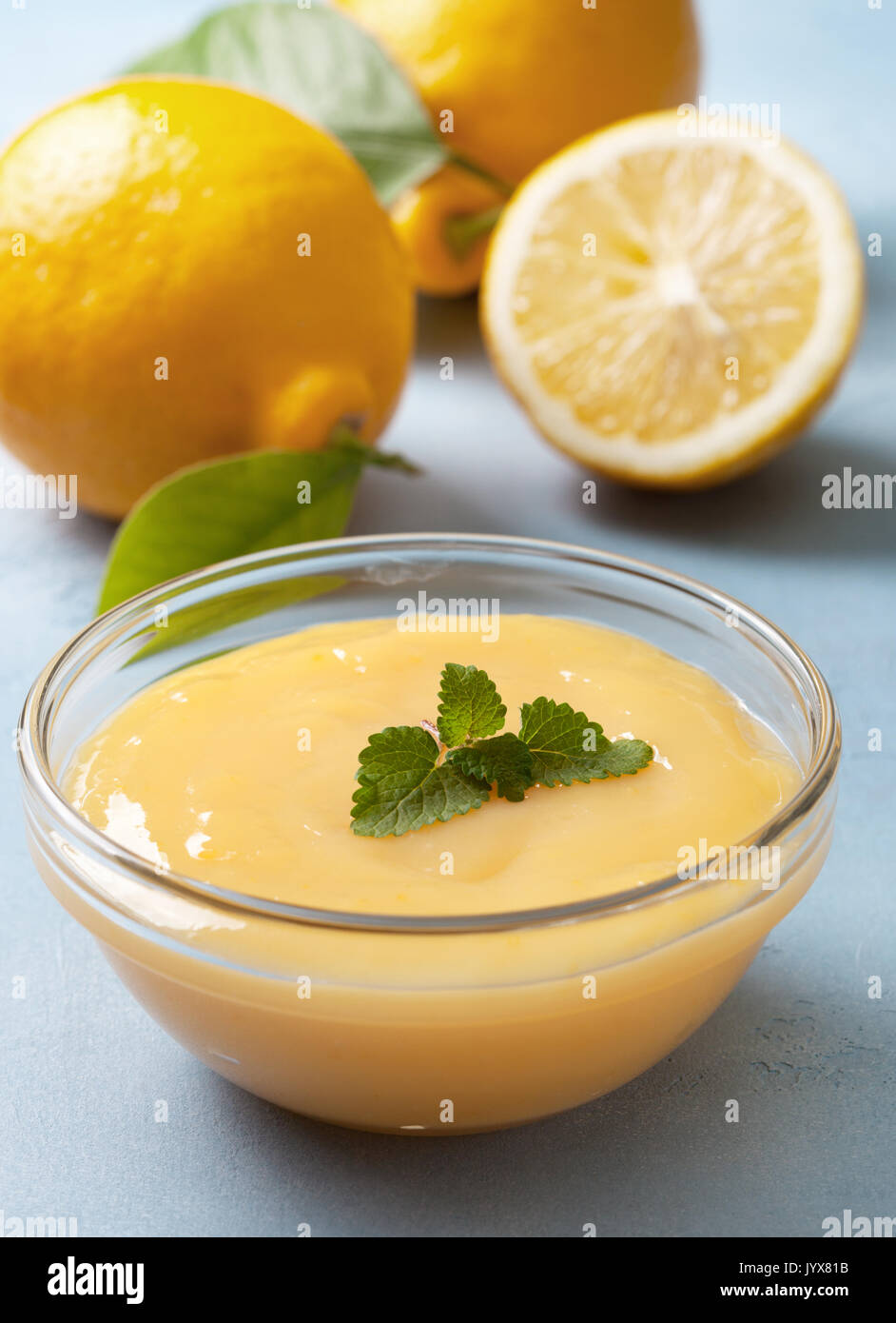 lemon curd in a glass bowl, fresh lemons on a blue background Stock Photo