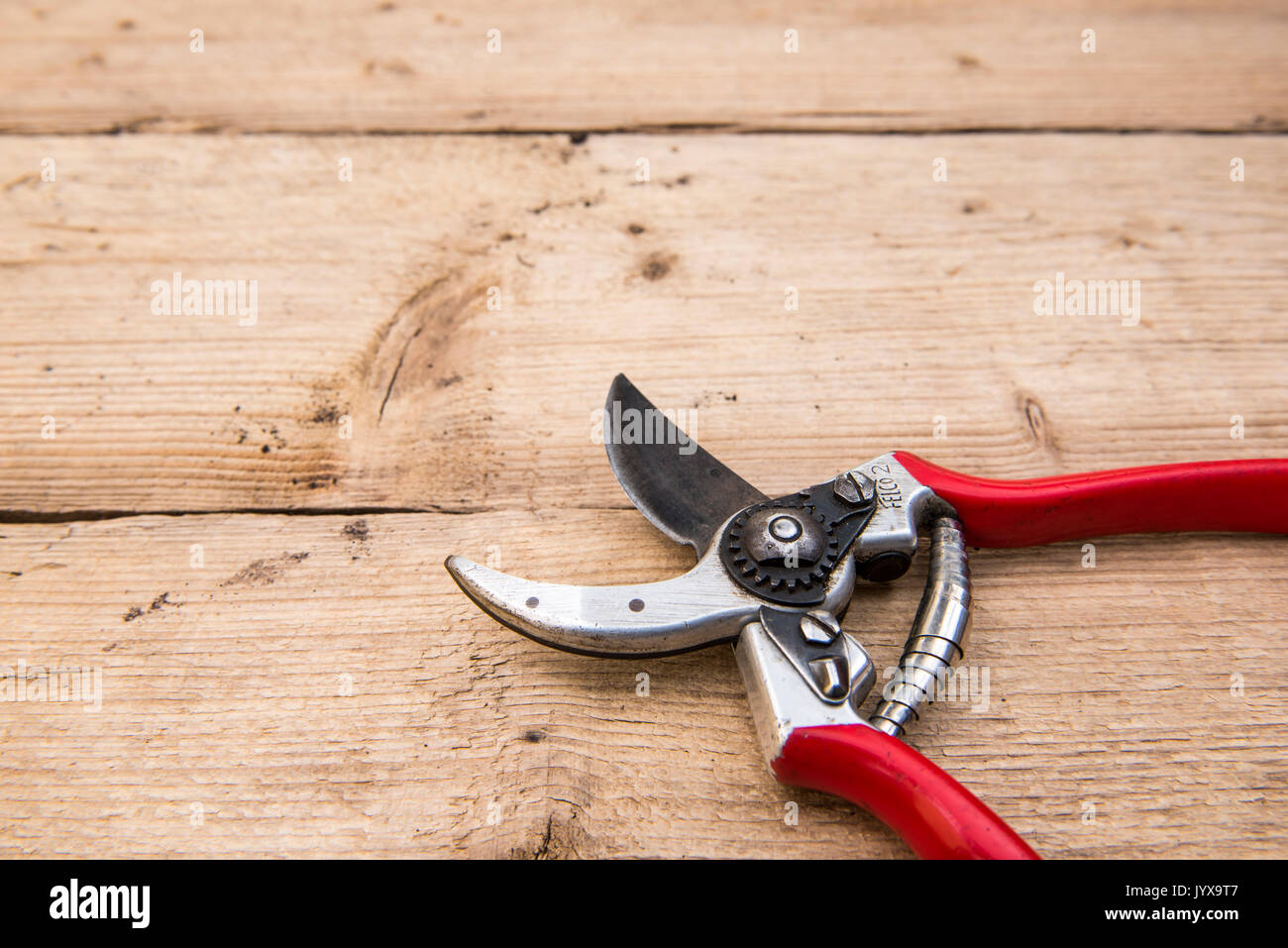 Pair of Felco secateurs laying open on a wooden bench. Stock Photo