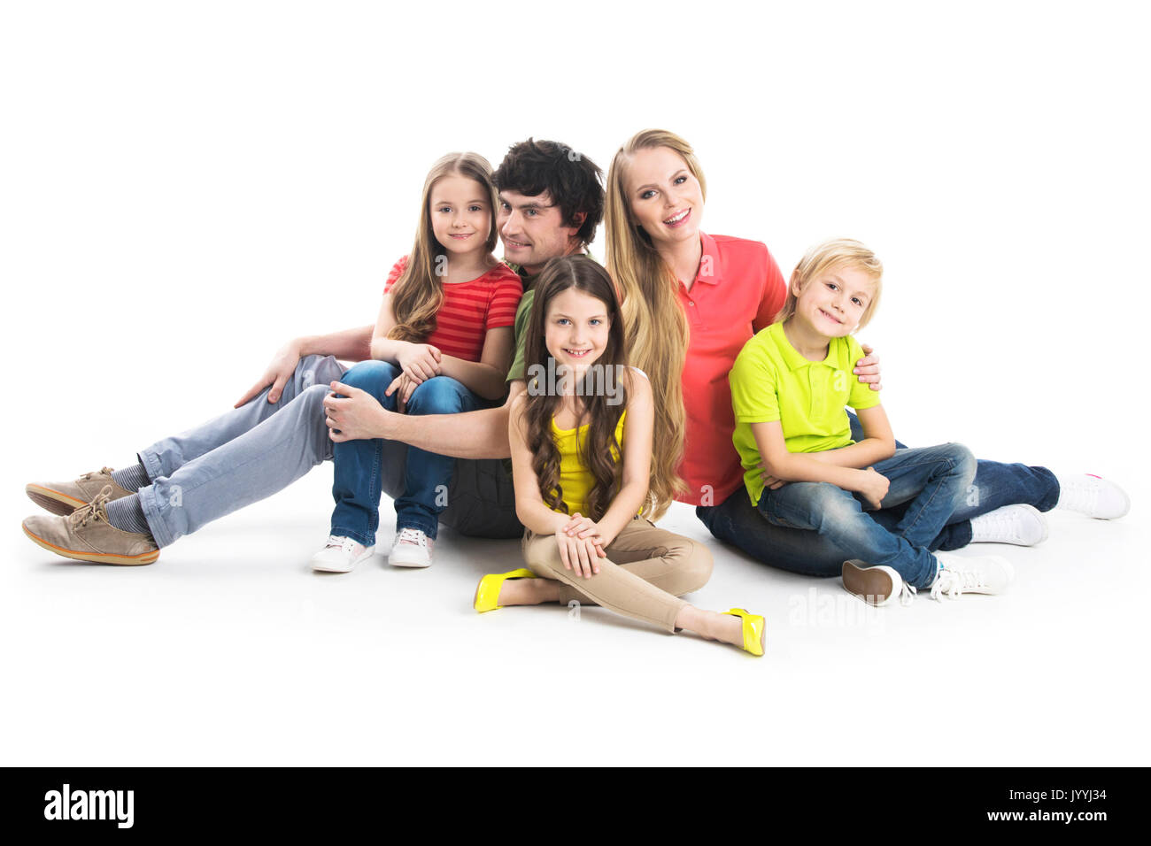 Happy smiling family of two parents and three children sitting on the floor studio isolated on white background Stock Photo
