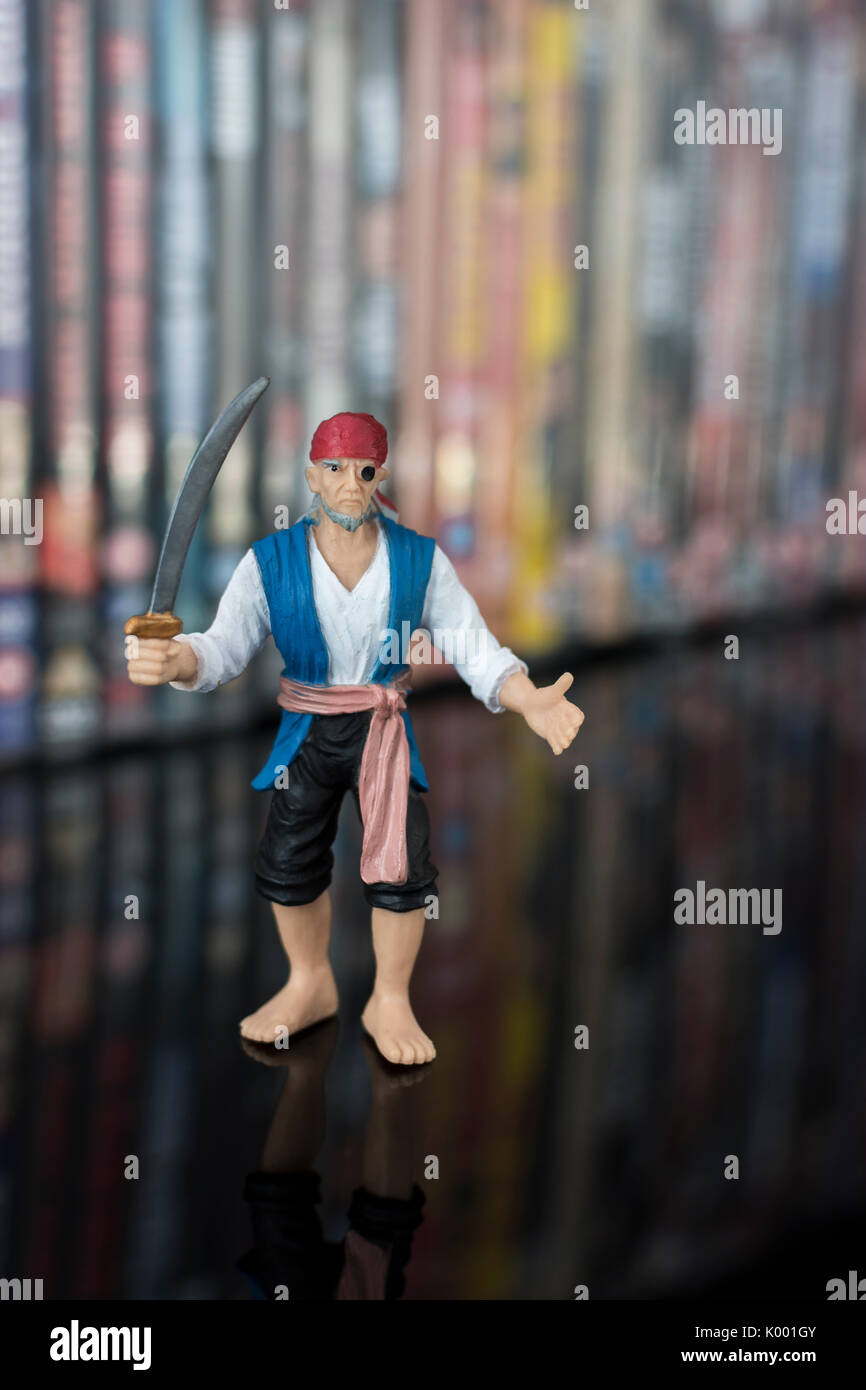 Sword wielding toy pirate standing in front of stacks of DVDs (Digital Versatile Disc) - metaphor software piracy, Chinese counterfeit goods, IP theft Stock Photo
