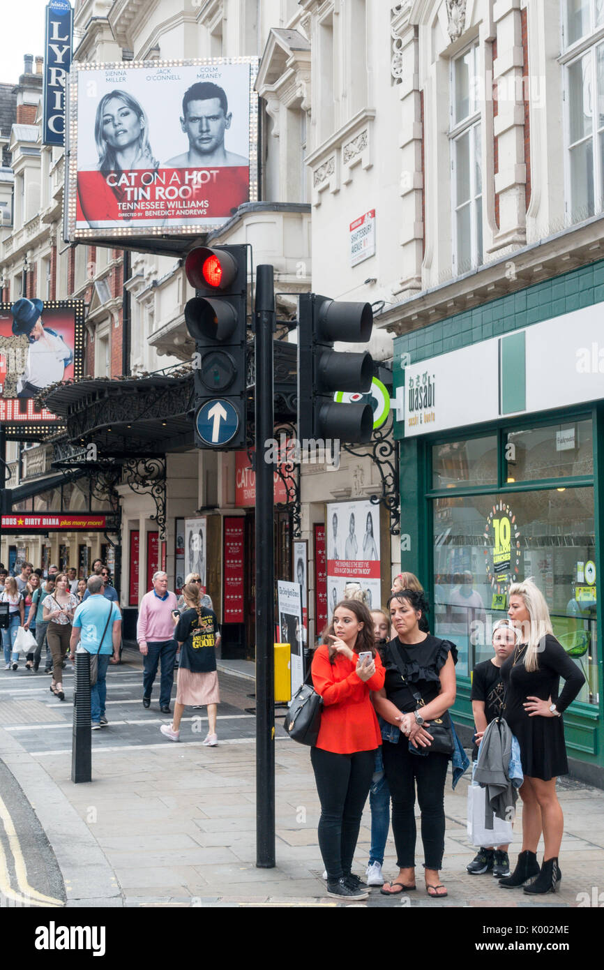A group of women tourists waiting to cross the road outside the Apollo Theatre Shaftesbury Ave, Soho, London W1D 7EZ, UK Stock Photo