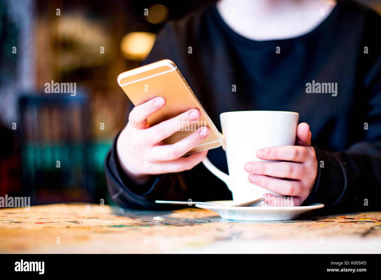 Holding and Texting On A Mobile or Cell Phone In A Cafe or Bar Stock Photo