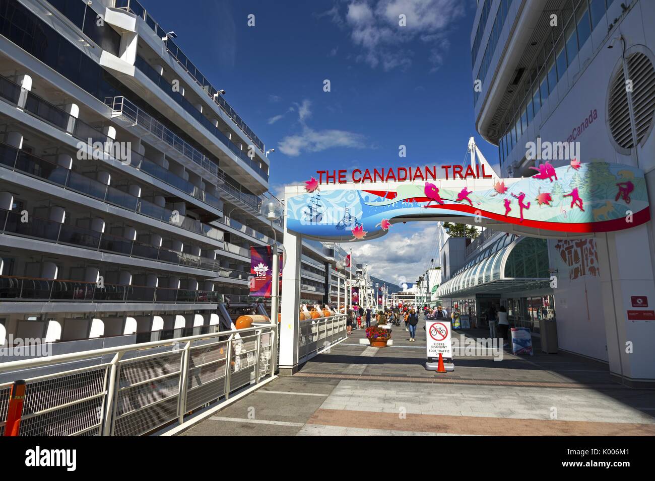 Tourist People walking on the Canadian Trail at Canada Place next to Big Cruise Ship docked in Port of Vancouver Harbor in British Columbia Canada Stock Photo