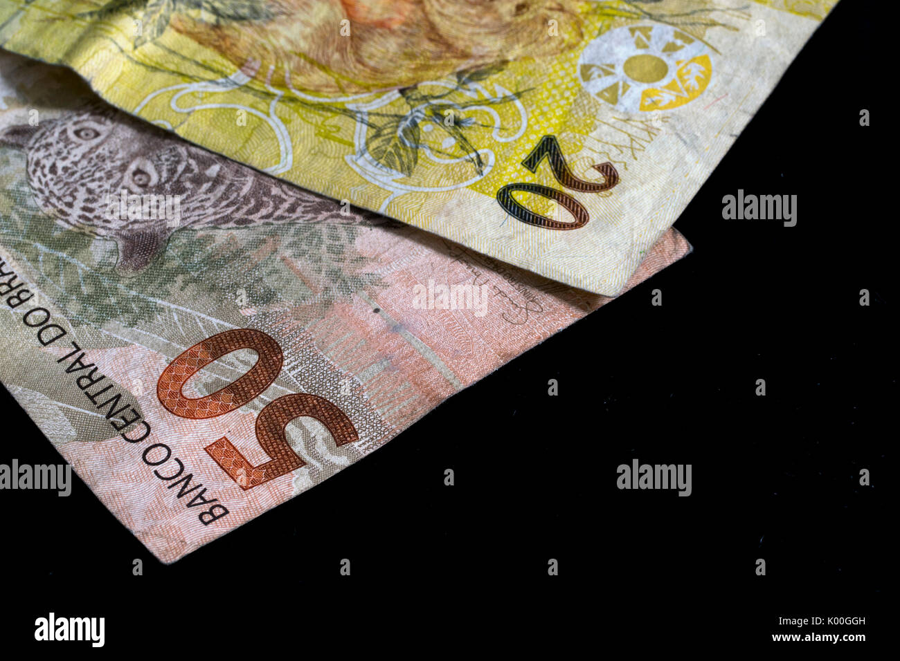 Two Brazilian Real money notes,of 50 and 20 value, currency of Brazil, on a black background, closeup macro Stock Photo