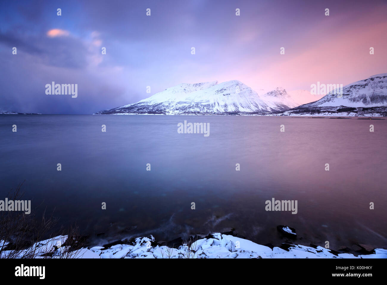 The sky turns pink at sunset and is reflected in the frozen sea Storfjorden Lapland Lyngen Alps Tromsø Norway Europe Stock Photo