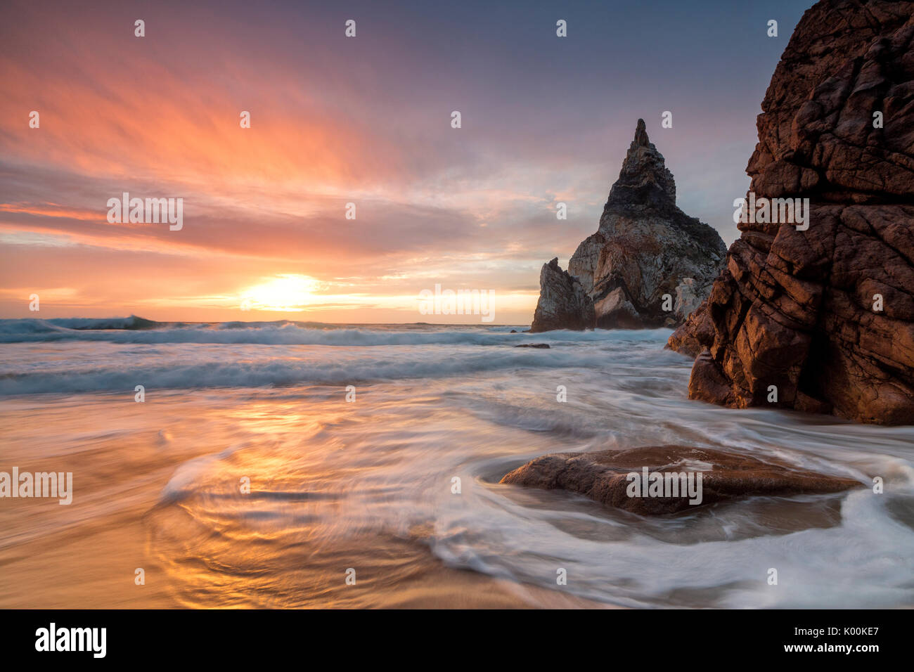 The fiery sky at sunset is reflected on the ocean waves and cliffs Praia da  Ursa Cabo da Roca Colares Sintra Portugal Europe Stock Photo - Alamy